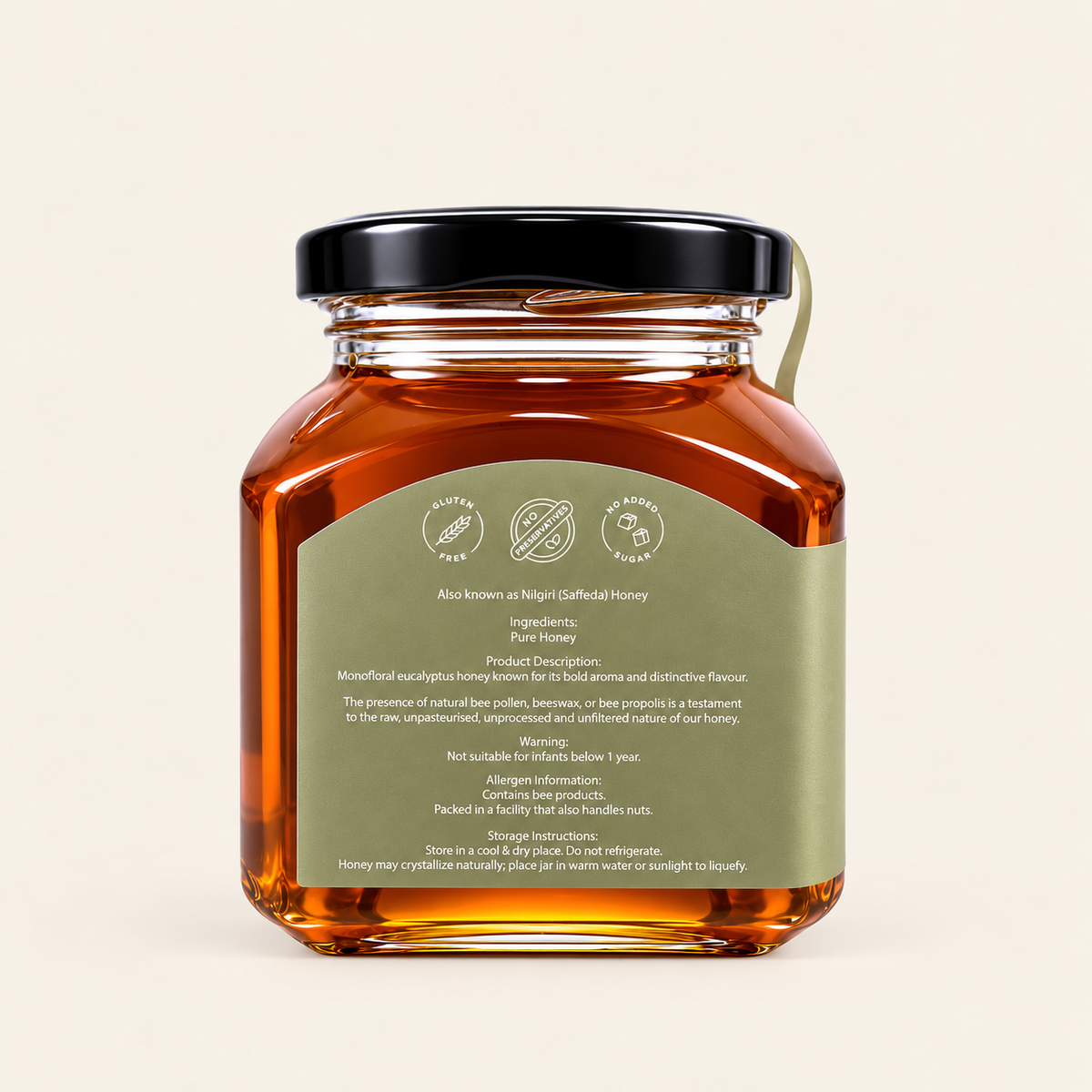 A glass jar of honey with a black lid and a green label, shown from the back against a light beige background.