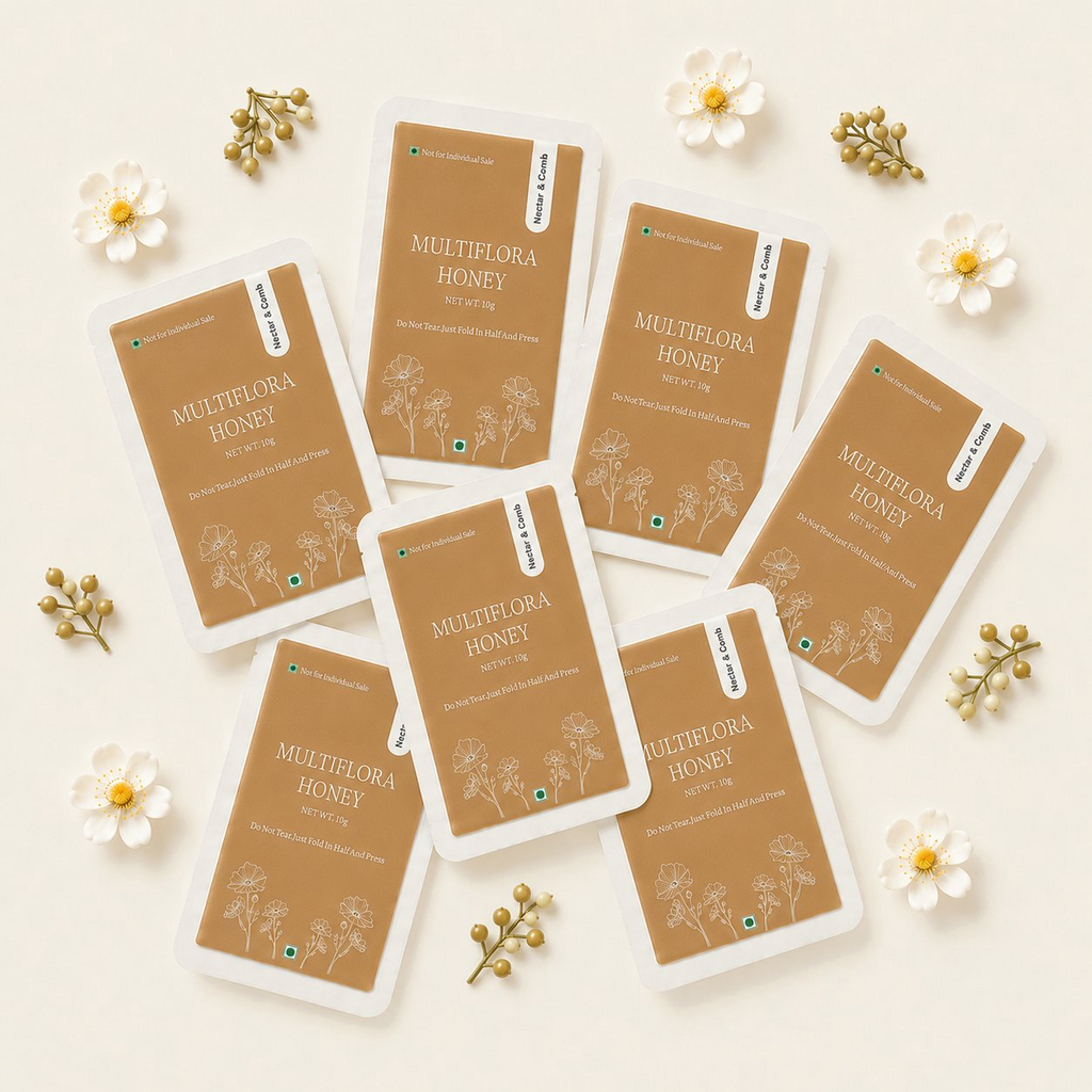 Multiple packages of Multiflora Honey on a light background with flowers and leaves.