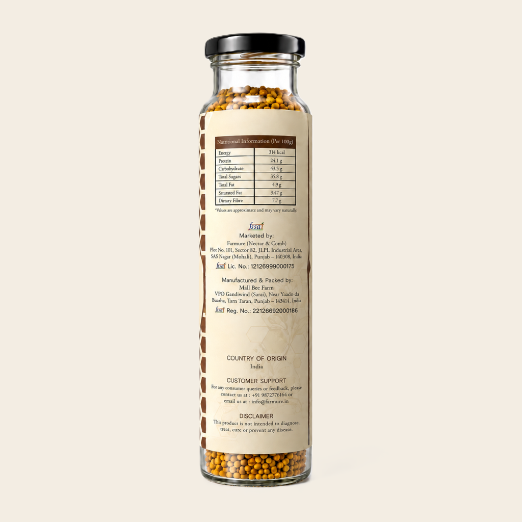 A clear glass jar filled with mustard seeds, featuring a black screw cap and a beige label with nutritional facts and product details, set against a solid off-white background.