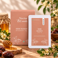 Nectar & Comb Sidr Honey product packaging shown with a large rectangular box and a single sachet, styled on a wooden surface with honey, dates, flowers, and a honey dipper.