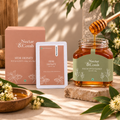Nectar & Comb Sidr Honey eucalyptus honey jar with a wooden honey dipper, alongside its pink packaging box and a single packet, styled on a stone slab with eucalyptus leaves and a wooden bowl of honey.