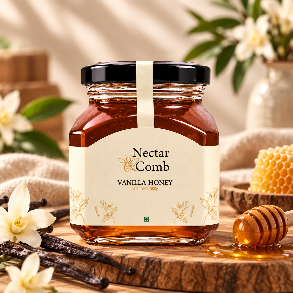 A jar of Nectar Comb Vanilla Honey centered on a wooden surface, surrounded by vanilla beans, white flowers, a honey dipper, and a honeycomb piece in a softly styled setting.