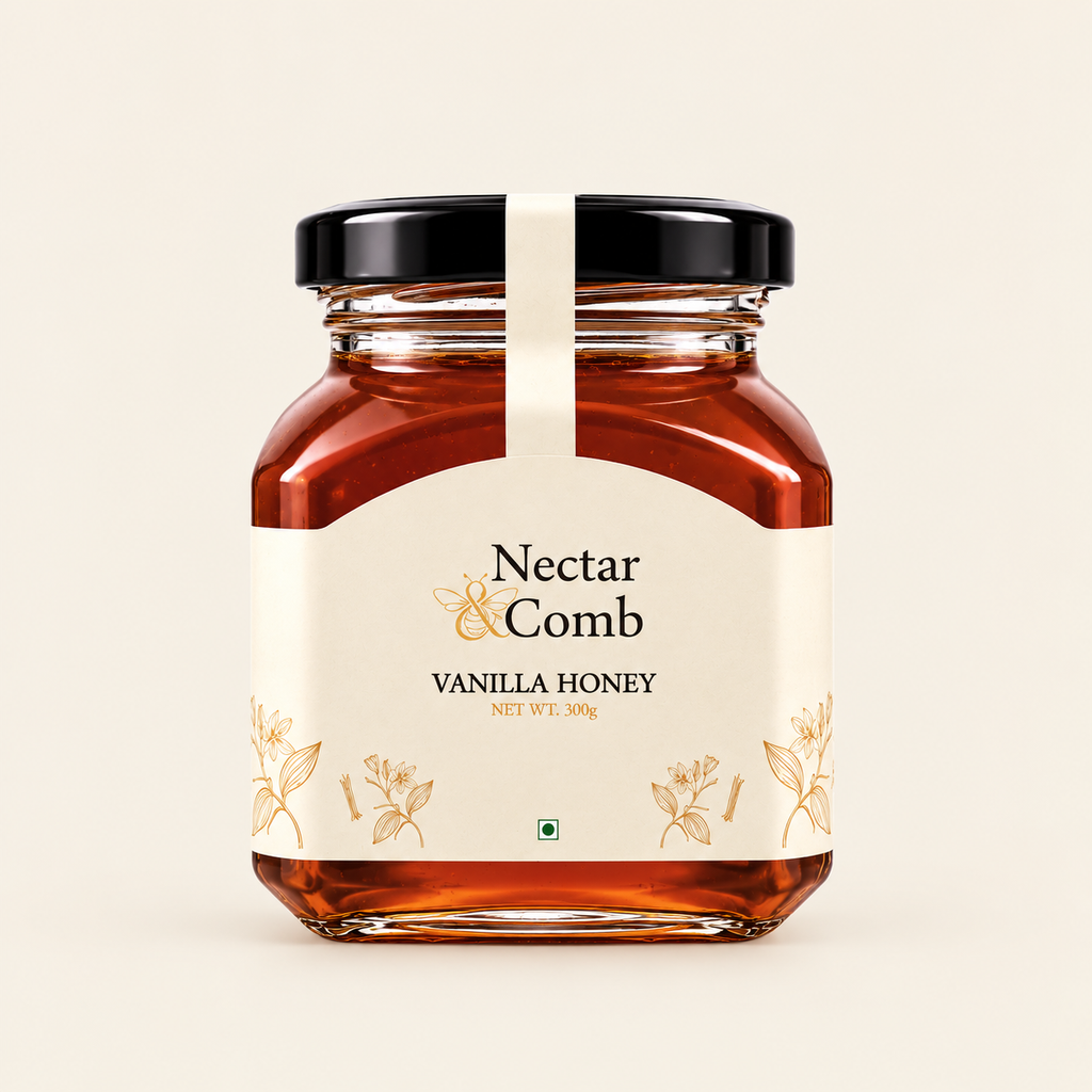 A glass jar of Nectar & Comb Vanilla Honey with a cream-colored label and a black lid, set against a solid off-white background.